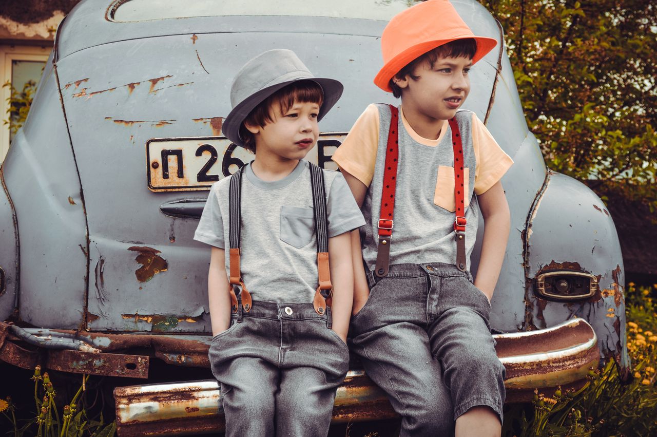 Crafting Captivating Headlines: Your awesome post title goes here Two boys in retro-style outfits sitting on a rusty car bumper outdoors.