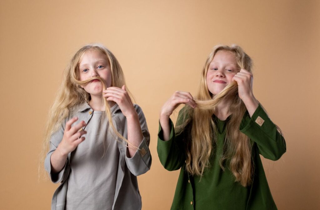 Mastering the First Impression: Your intriguing post title goes here Charming twin girls with long blonde hair making funny faces in a studio setting.